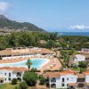 Vista aerea di un complesso con piscina vicino al mare.