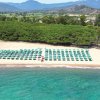 Spiaggia con lettini e ombrelloni verdi, acqua turchese.