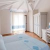 Camera da letto luminosa con arredo bianco e dettagli azzurri.