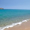 Spiaggia sabbiosa con mare turchese e isolotti all'orizzonte.