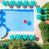 Piscina con ombrelloni verdi vista dall'alto.