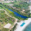 Spiaggia naturale con ombrelloni e mare.