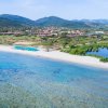 Spiaggia con mare cristallino e villette sullo sfondo.