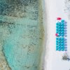 Ombrelloni allineati su spiaggia bianca accanto al mare trasparente.