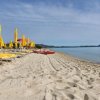 Spiaggia con lettini e ombrelloni gialli.