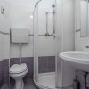 Un piccolo bagno con doccia angolare, lavandino e WC con piastrelle viola e bianche.
