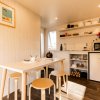Cucina compatta con tavolo, sgabelli e scaffali aperti.