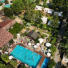 Vista aerea di una piscina circondata da alberi, ombrelloni e edifici.