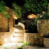 Scalinata di pietra illuminata di notte, circondata da vegetazione.