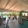 Interno di un bar con vista sulla piscina esterna, tavoli e sedie moderne.