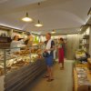 Interno di un negozio di alimentari con pani assortiti e persone che fanno acquisti.