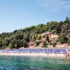 Spiaggia con ombrelloni blu e verde collina.