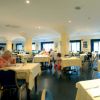 Sala da pranzo con tavoli apparecchiati e persone sedute.