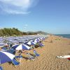 Spiaggia con ombrelloni blu e bianchi lungo la riva.