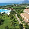 Vista aerea di un resort con piscina, giardini e vista mare.