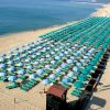 Spiaggia con ombrelloni blu e lettini ordinati.