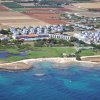 Vista aerea di una località balneare con edifici bianchi e mare turchese.