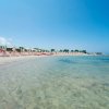 Spiaggia con lettini e ombrelloni su sabbia dorata, mare limpido.