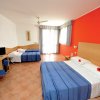 Camera d'albergo con due letti matrimoniali, pareti rosse e bianche.