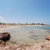 Spiaggia con ombrelloni su sabbia e rocce.