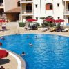 Una piscina con ombrelloni rossi e lettini, circondata da un edificio residenziale.