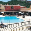 Un resort con piscina centrale, ombrelloni bianchi e edifici colorati intorno.