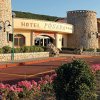 Ingresso dell'Hotel Posada, con facciata in pietra e aiuole fiorite lungo il vialetto.