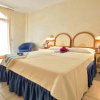 Camera d'albergo con letto matrimoniale, comodini e una poltrona blu.