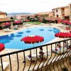 Piscina all'aperto circondata da sedie a sdraio e ombrelloni rossi.