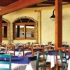 Sala ristorante con tavoli apparecchiati, sedie colorate e archi in legno.