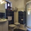 Bagno con piastrelle blu, lavabo, bidet, WC e cabina doccia semicircolare.