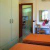 Camera con due letti singoli, armadio bianco e scrivania. Porta aperta verso la cucina.