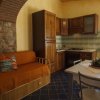 Cucina con divano arancione, tavolo bianco e arredi in legno. Finestra sulla destra.