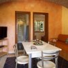 Sala con tavolo bianco, divano arancione e muri in pietra. Due porte sullo sfondo.