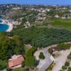 Veduta aerea di un paesaggio costiero con case, alberi e una spiaggia.
