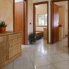 Interno di una casa con mobili in rattan, pavimento piastrellato e piante.