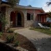 Casetta in pietra con portico, sdraio e giardino curato con piante.