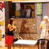 Due persone parlano su un palco, con un murale colorato sullo sfondo.