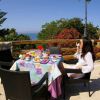 Una donna seduta a un tavolo all'aperto con colazione e vista sul mare.