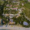 Vista aerea di un complesso turistico con spiaggia attrezzata e verde circostante.