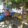 Un'altalena e scivolo in un'area giochi all'aperto sotto gli alberi.