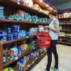 Persona con un cestino rosso che sceglie prodotti in un piccolo negozio di alimentari.
