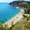 Vista panoramica di una spiaggia con acque turchesi e scogliere verdi.