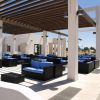 Area lounge all'aperto con divani blu sotto una tettoia a griglia.
