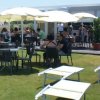 Persone sedute a tavoli all'aperto con ombrelloni gialli.
