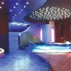 Piscina interna elegante con disegni luminosi sul soffitto.