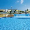 Piscina all'aperto con acqua blu chiaro e ombrelloni gialli.