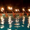 Persone di notte in piscina con torce accese.