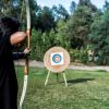 Persona che scocca una freccia verso un bersaglio in un campo.