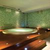 Spa con vasca idromassaggio circondata da mosaico verde.
